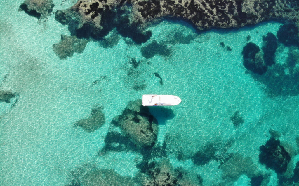 Luftaufnahme eines privaten Bootes in kristallklarem Wasser auf Mallorca