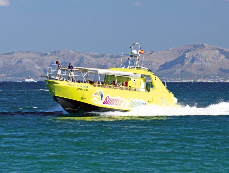 Beau paysage avec la côte de Majorque en arrière-plan et le bateau de l'excursion des criques et des grottes naviguant.