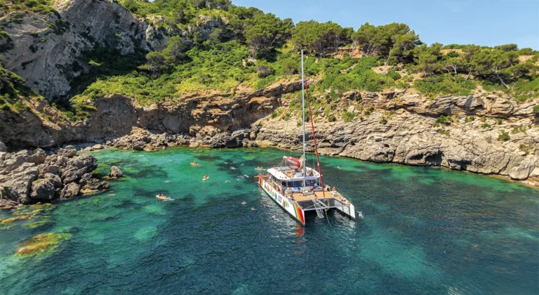Aerial view of a catamaran anchored in a beautiful coastal landscape in Alcúdia, Mallorca